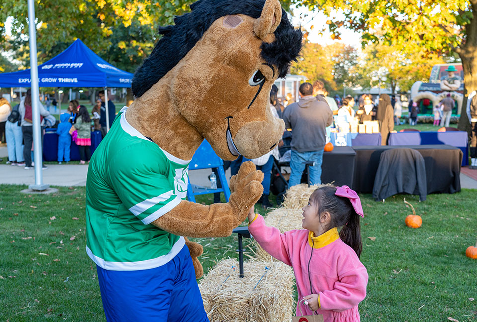 Mascot Bolt high-fives a young girl.